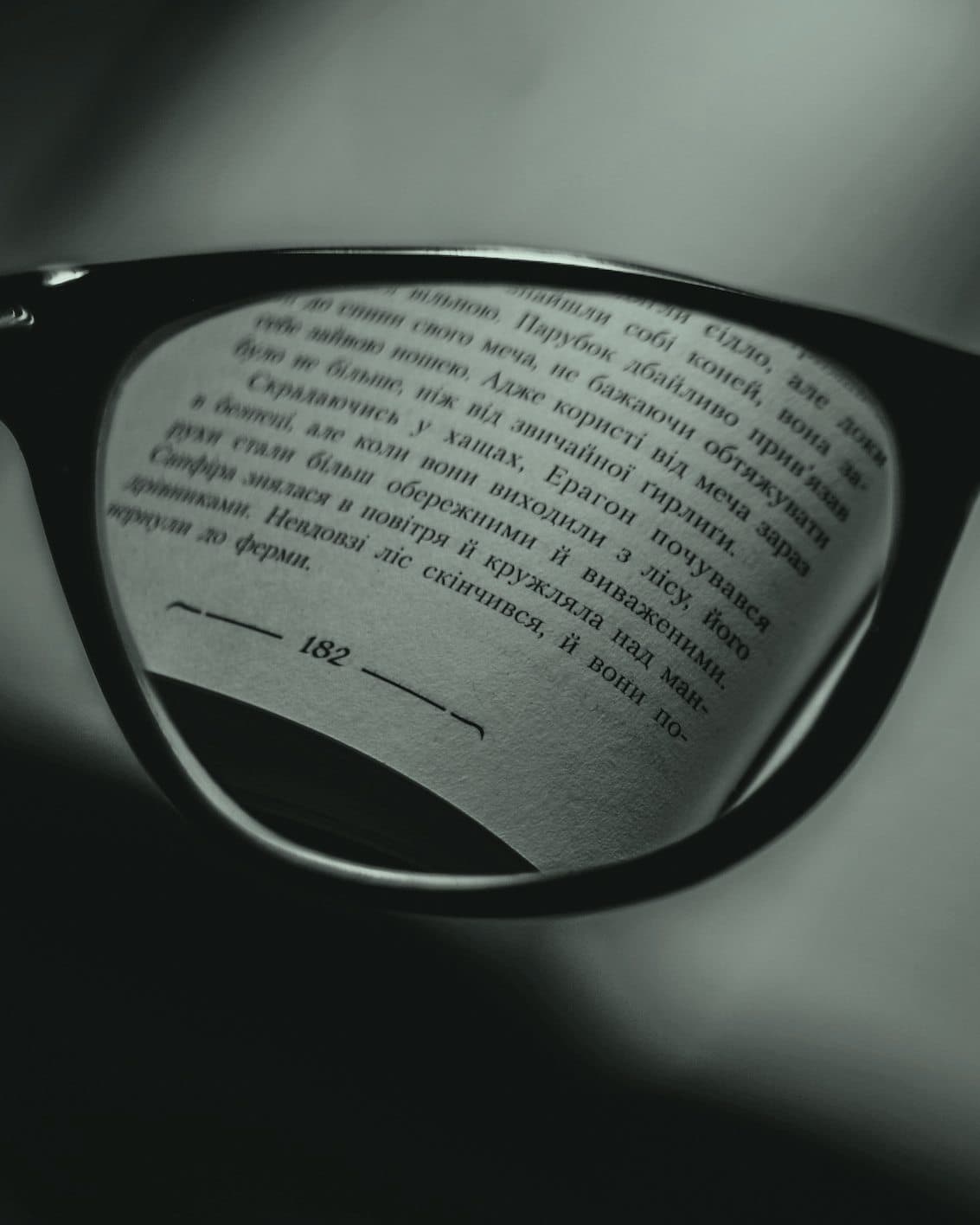 Reading glasses over an open book: the page is a blur everywhere except through the lens, where the text is sharp enough to read.
